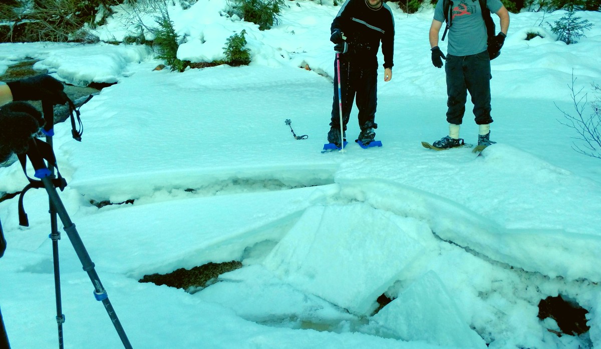 Snowshowers looking onto a large hole in the ice